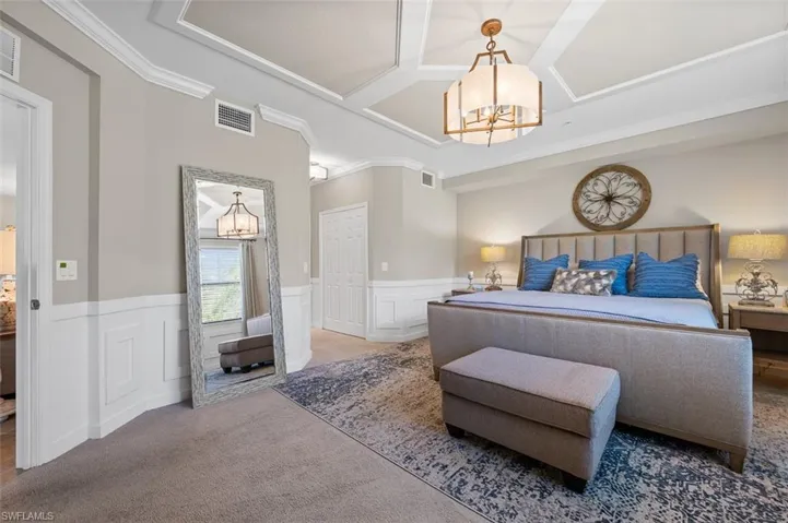 Bedroom featuring a notable chandelier, coffered ceiling, carpet floors, and crown molding