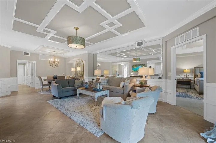 Living room featuring a notable chandelier, coffered ceiling, and light tile flooring
