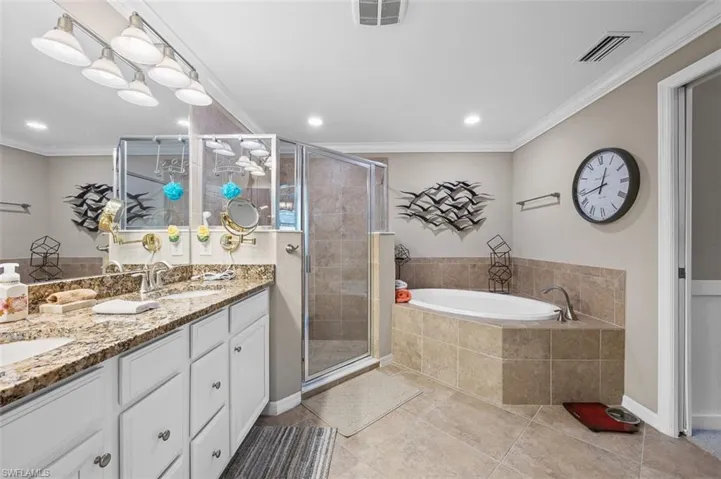 Bathroom featuring tile floors, crown molding, shower with separate bathtub, and dual bowl vanity