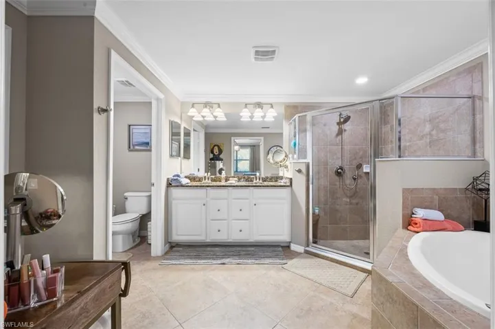 Full bathroom with tile flooring, ornamental molding, toilet, and plus walk in shower