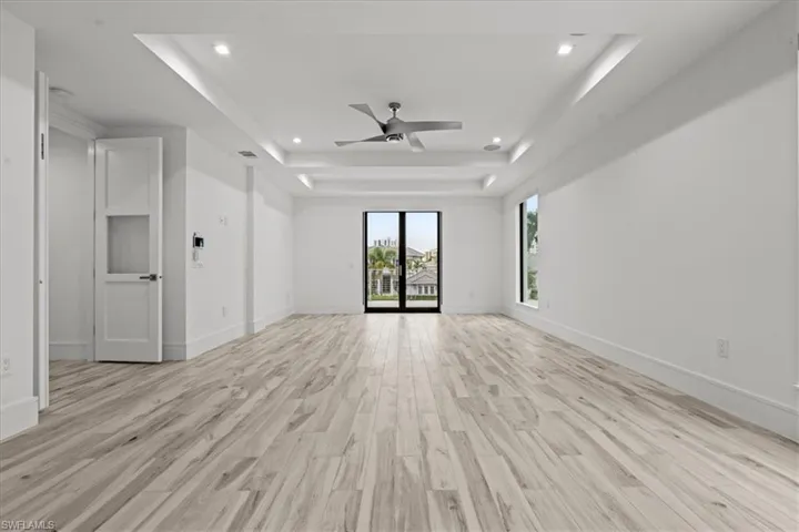 Unfurnished living room with light wood-style floors, recessed lighting, a raised ceiling, and a ceiling fan