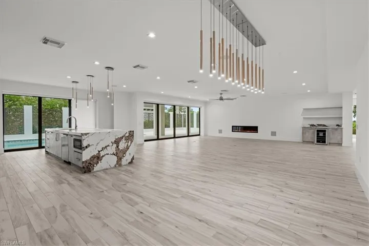 Living area with recessed lighting, a glass covered fireplace, light wood finished floors, wine cooler, and a ceiling fan