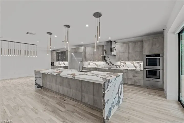 Kitchen featuring tasteful backsplash, modern cabinets, a spacious island, light stone counters, and recessed lighting