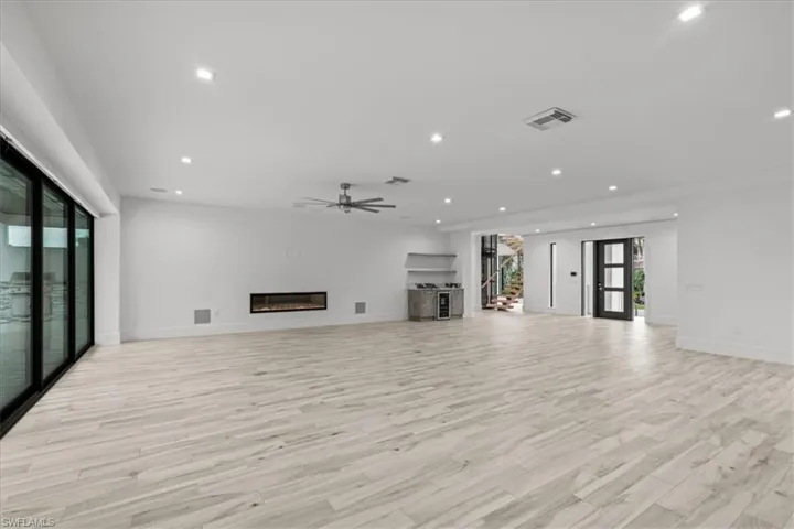 Unfurnished living room featuring a glass covered fireplace, light wood-style floors, recessed lighting, ceiling fan, and french doors