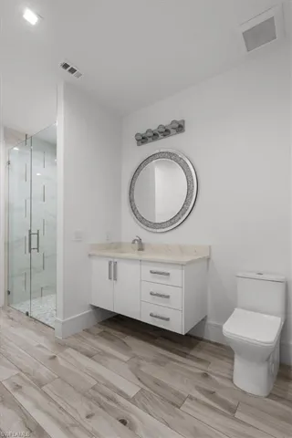 Bathroom featuring vanity, a marble finish shower, and wood tiled floors