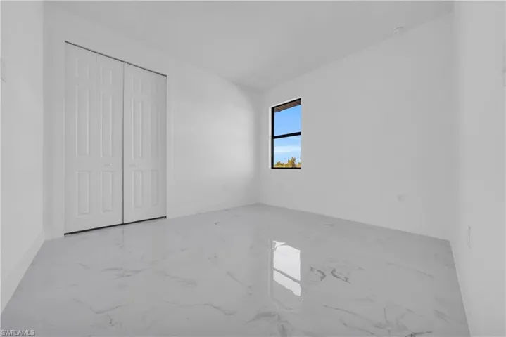 Unfurnished bedroom with light marble finish floors and a closet