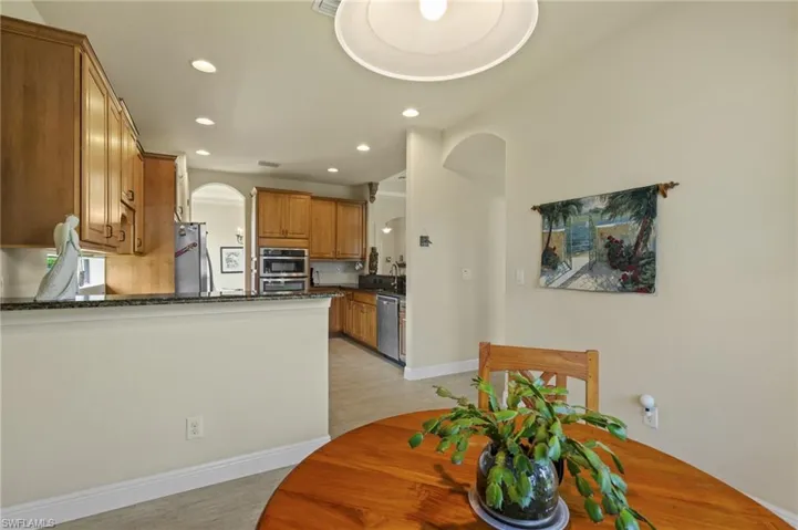 Dining area with arched walkways, recessed lighting, and light wood-style flooring
