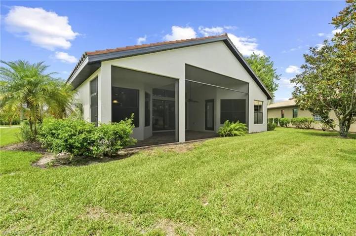 Back of house with stucco siding, a yard, a ceiling fan, and a sunroom
