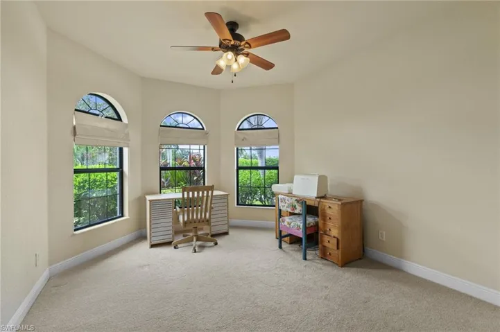 Carpeted home office with baseboards and a ceiling fan