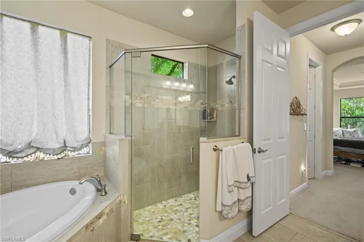 Full bathroom featuring a shower stall, a garden tub, ensuite bath, and wood finished floors