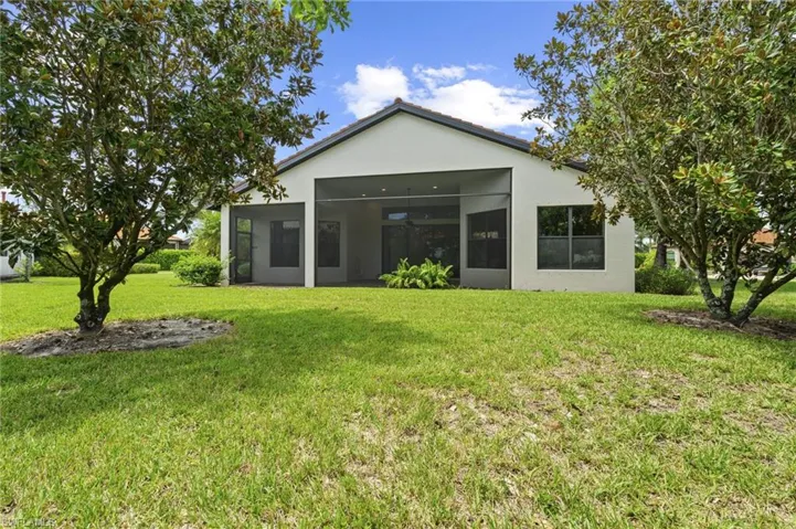 Back of property with stucco siding, a lawn, and a patio area