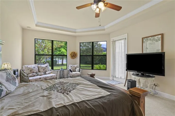 Bedroom featuring carpet floors, a tray ceiling, crown molding, and ceiling fan