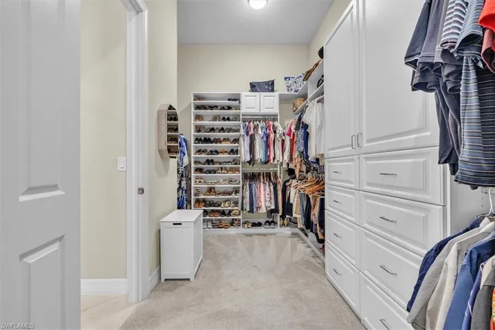 Custom closet system with extensive built-in storage, white cabinetry, and recessed lighting