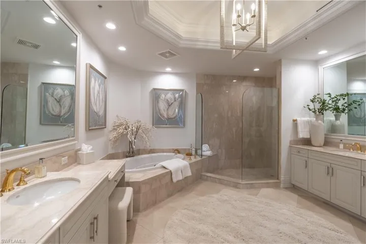 Primary bathroom with dual sinks, walk in shower and separate tub and two water closets