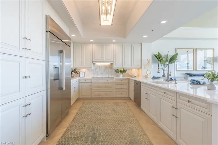 Kitchen featuring white cabinets, raised ceiling, stainless appliances