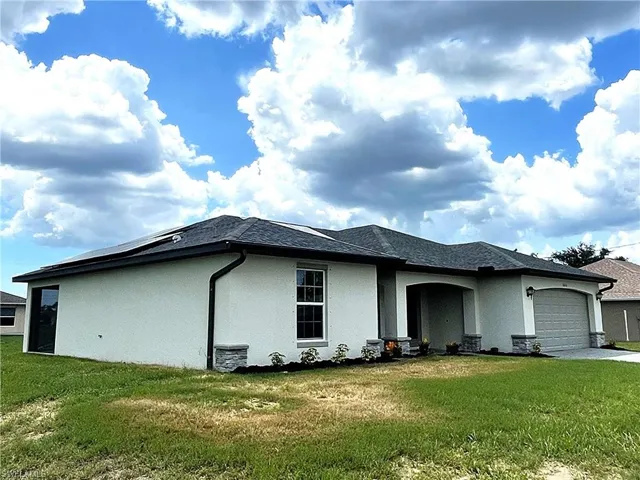 Single story home on a 3-lot site, with shingle roof and electric solar panels.