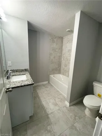 Guest Bathroom with shower/tub combination, single vanity with granite countertop, tile floors, and linen closet.