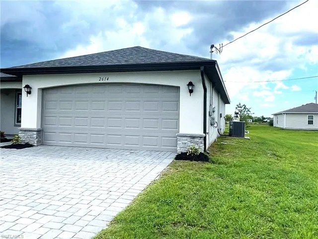 Two-car garage with paver driveway and exterior stone work.
