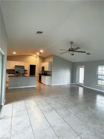 Great Room looking towards entry door, with vaulted ceiling, tile floors, ceiling fan, and lots of natural light.