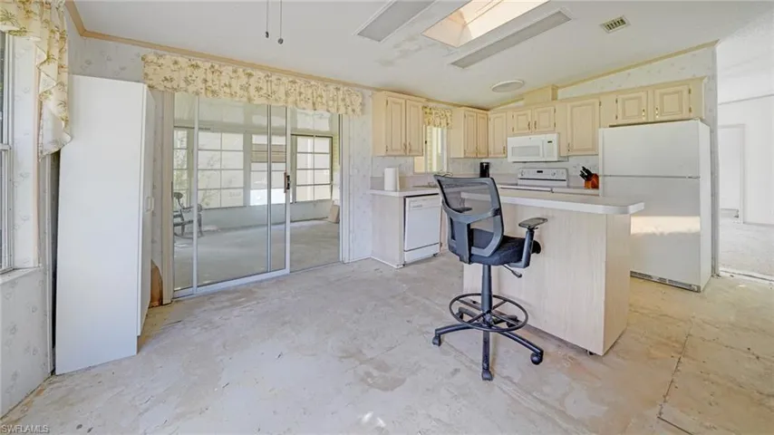 Kitchen featuring a kitchen island, a kitchen breakfast bar, white appliances, lofted ceiling with skylight, and ornamental molding