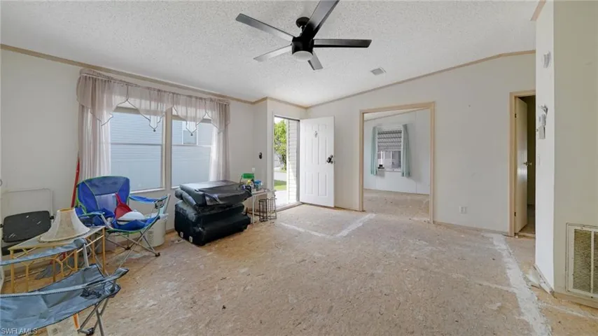 Misc room with lofted ceiling, ceiling fan, ornamental molding, and a textured ceiling