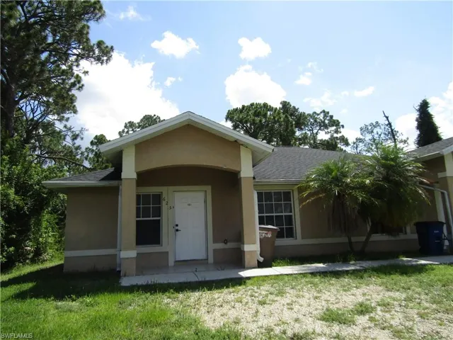 Stucco exterior with a covered entry, white paneled door, and multiple windows