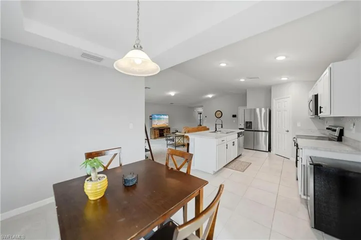 Dining space with vaulted ceiling, light tile patterned floors, and recessed lighting