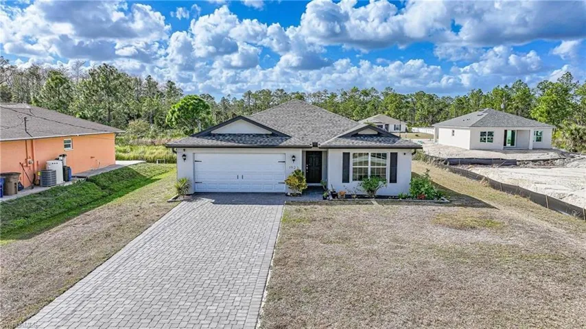 View of front of home featuring decorative driveway, a garage, stucco siding, and a shingled roof