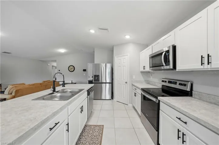 Kitchen with appliances with stainless steel finishes, white cabinets, light countertops, open floor plan, and light tile patterned floors