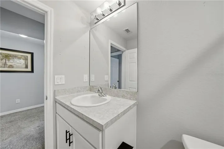 Half bath featuring vanity, carpet floors, and a textured wall