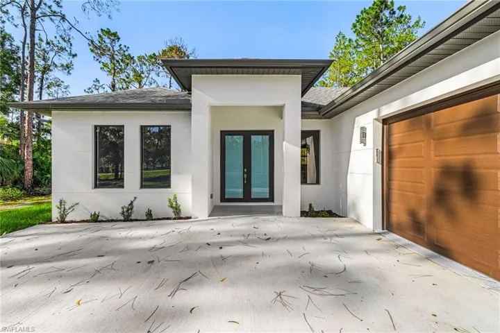 Entrance to property with a shingled roof, french doors, driveway, a garage, and stucco siding