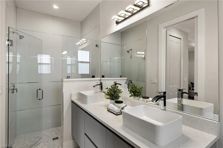 Full bathroom featuring a shower stall and double vanity