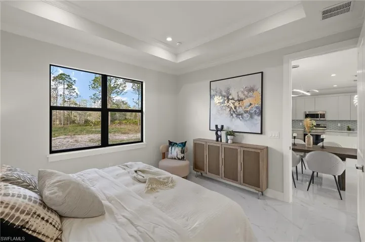 Bedroom featuring marble finish flooring, a tray ceiling, recessed lighting, and ornamental molding