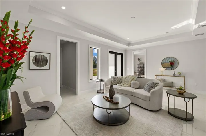 Living room featuring a tray ceiling, marble finish flooring, ornamental molding, and recessed lighting