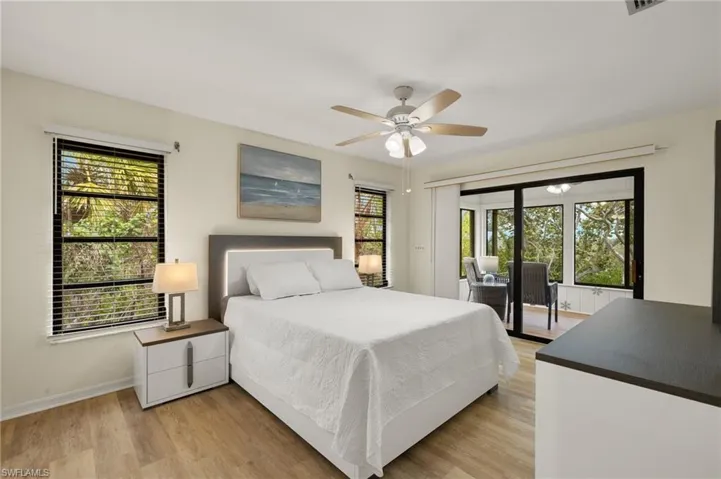 Bedroom with baseboards, access to exterior, light wood-style flooring, and ceiling fan