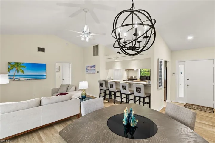Dining room with ceiling fan with notable chandelier, visible vents, wood finished floors, and baseboards