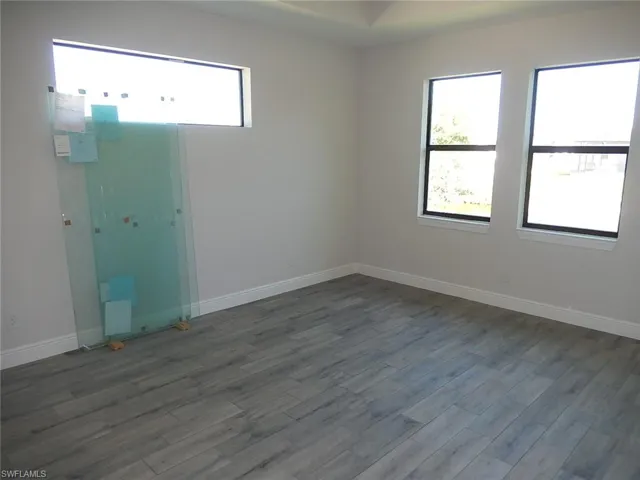 Empty room featuring dark wood-style flooring and baseboards