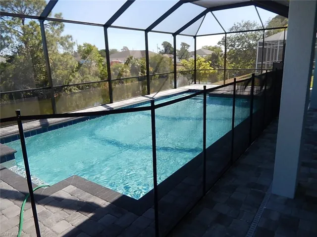 Outdoor pool with a water view, glass enclosure, and a sunroom