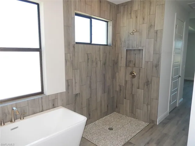 Bathroom featuring a freestanding bath, a tile shower, and wood finished floors