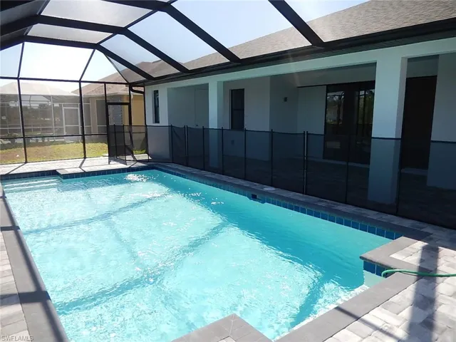 Outdoor pool featuring glass enclosure, a patio area, and a sunroom