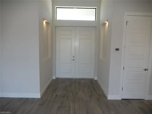 Foyer with baseboards and dark wood-style flooring