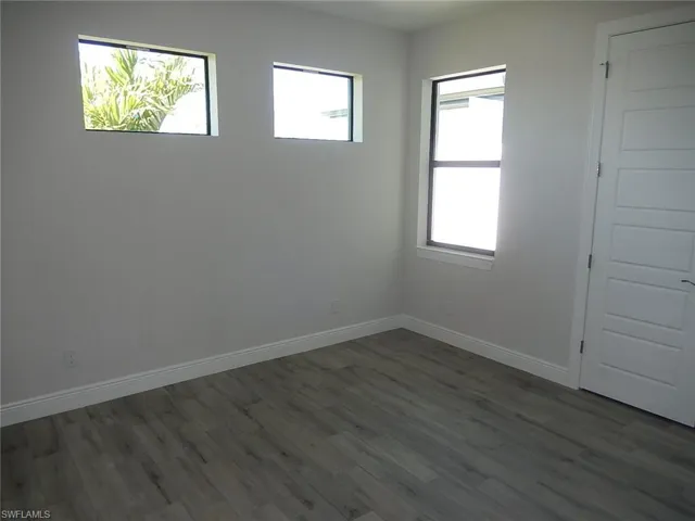 Spare room featuring dark wood finished floors and baseboards