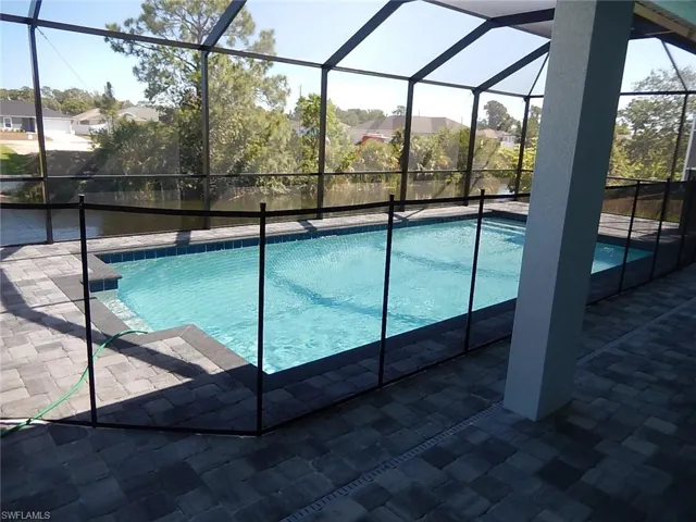 Outdoor pool featuring glass enclosure, a sunroom, and a patio