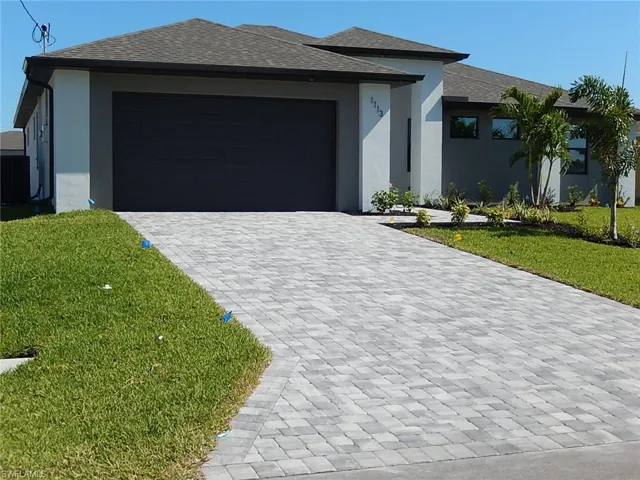 View of front of property with a front lawn, decorative driveway, stucco siding, roof with shingles, and a garage