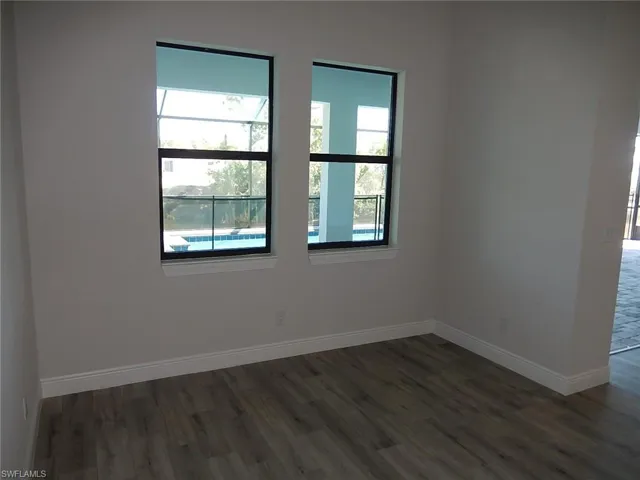 Unfurnished room featuring dark wood-type flooring and baseboards