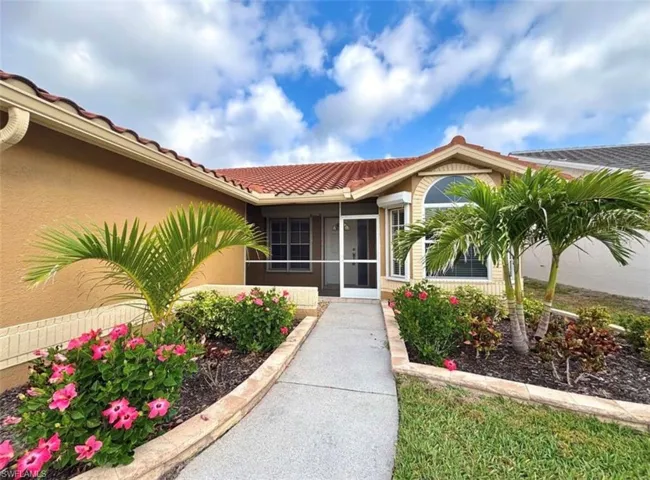 Doorway to property featuring a sunroom, a tiled roof, and stucco siding