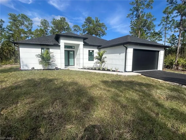 Prairie-style home with a garage, a front yard, driveway, and roof with shingles
