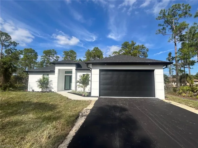 View of front facade featuring asphalt driveway, a front yard, a garage, and roof with shingles