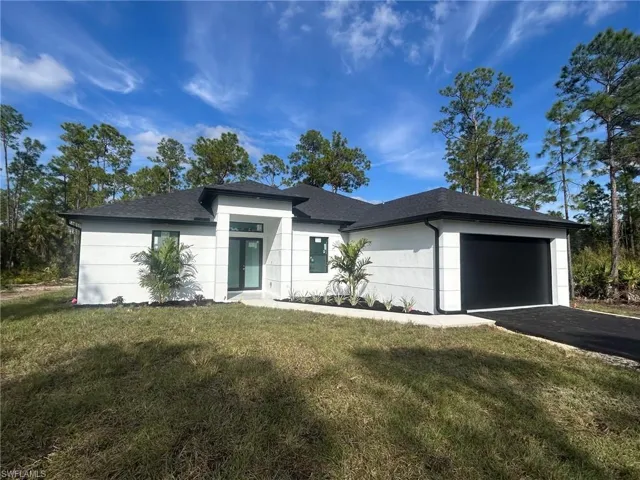 Prairie-style house featuring a garage, a front lawn, a shingled roof, and asphalt driveway