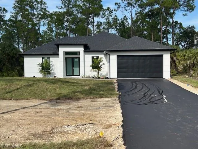 View of front of home with asphalt driveway, a front yard, an attached garage, and a shingled roof